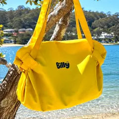 Yellow Billy tote hanging from a tree by the water